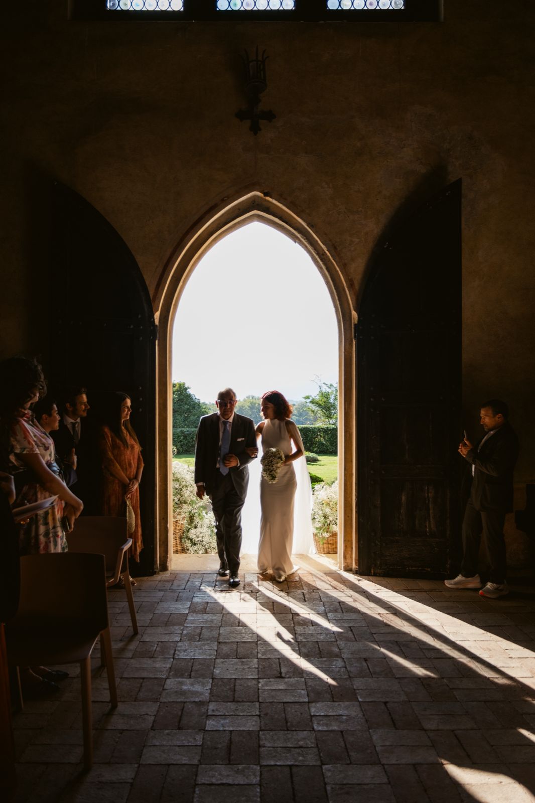 The bride walks into the church through the Gothic doorway, against the light