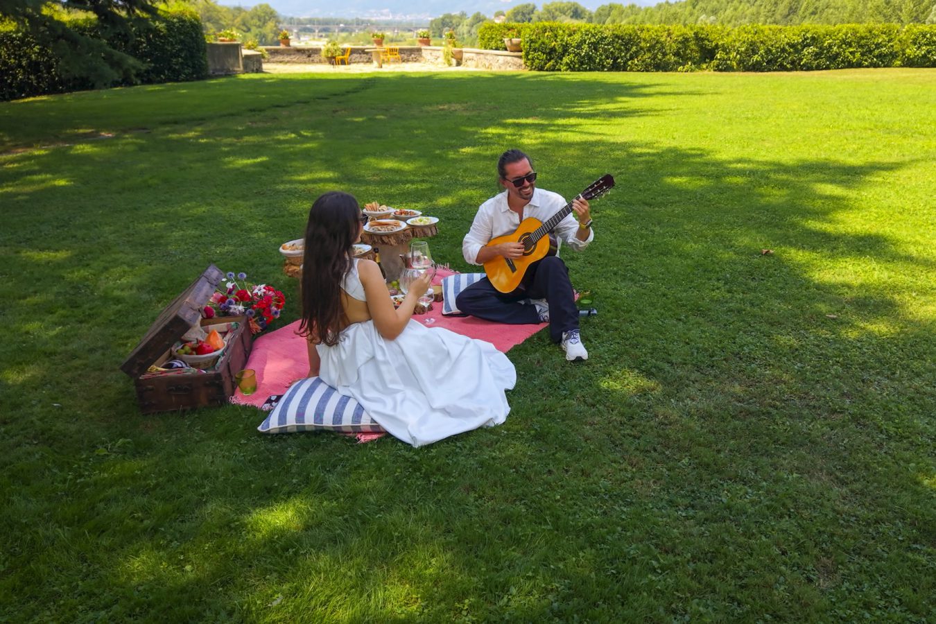 Two guests on a blanket on the lawn, one playing the guitar